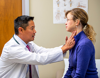 A care provider checking the neck of a patient.