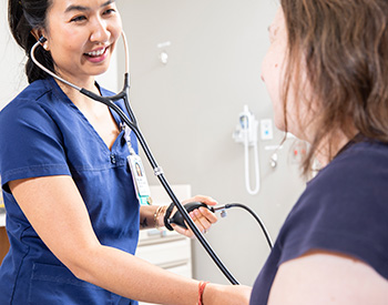 Care provider using a stethoscope on a patient.