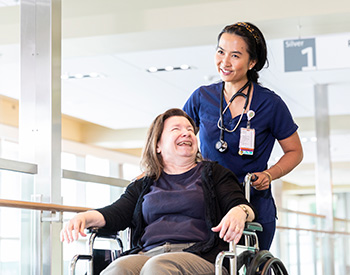 A care provider pushing a patient in a wheelchair.